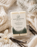 Snowfall Vanilla Snow Melts package surrounded by vanilla beans, a vanilla flower, and cozy knit fabric, evoking a warm, natural, and eco-friendly ambiance.